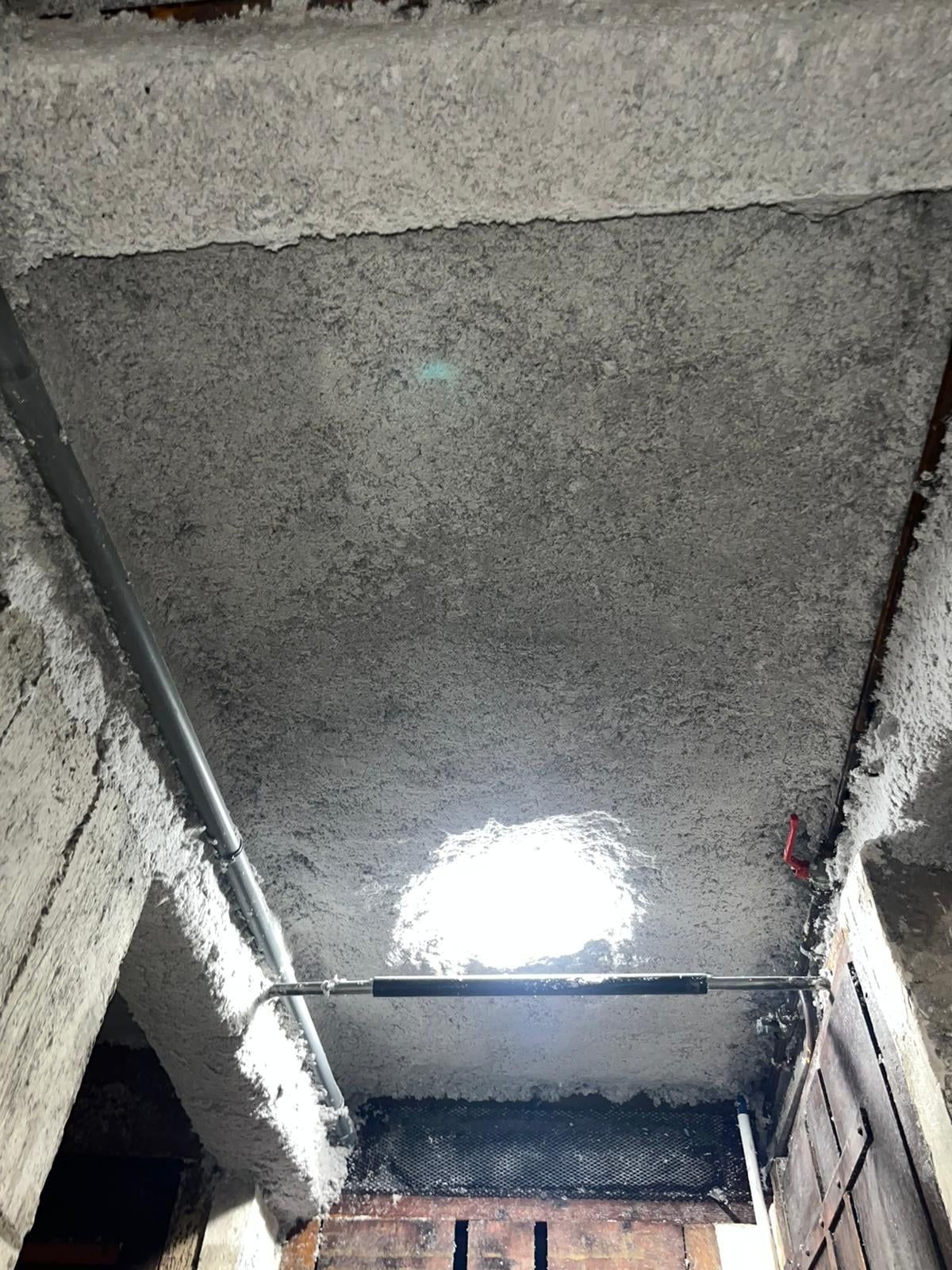 Plafond d'une cave recouvert d'isolant projeté, autour d'une lampe